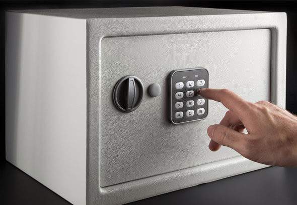 ALS - Hand opens a combination lock on the safe, a light safe on a dark background